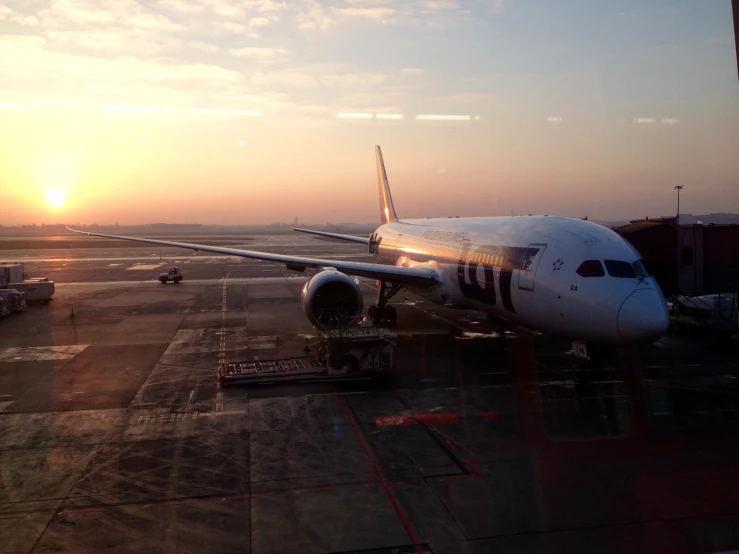 an airplane on the tarmac at an airport at sunset