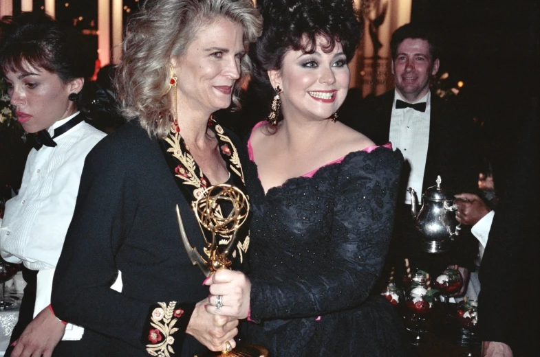 two women hugging each other while holding trophies