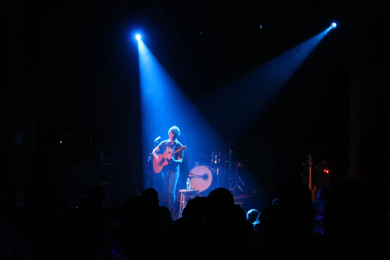 a person on stage playing music while others watch