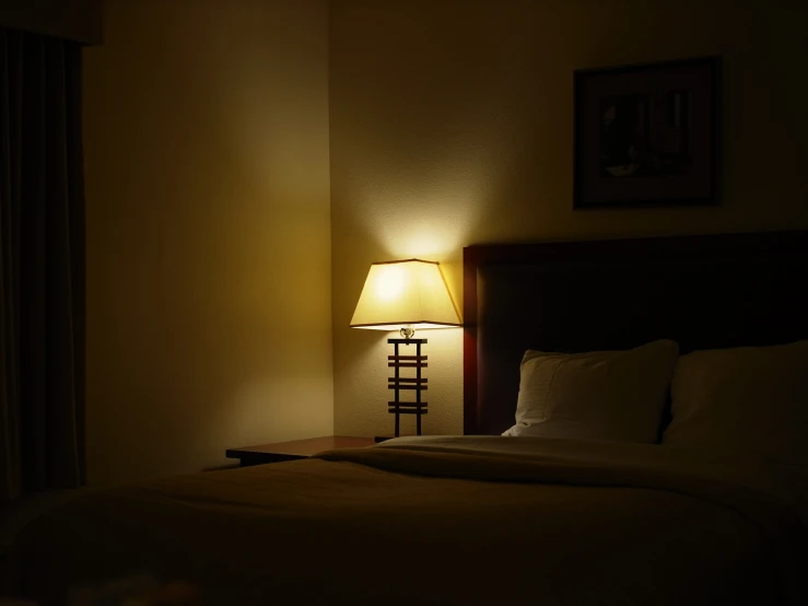 there is a lamp sitting on the corner of a bed