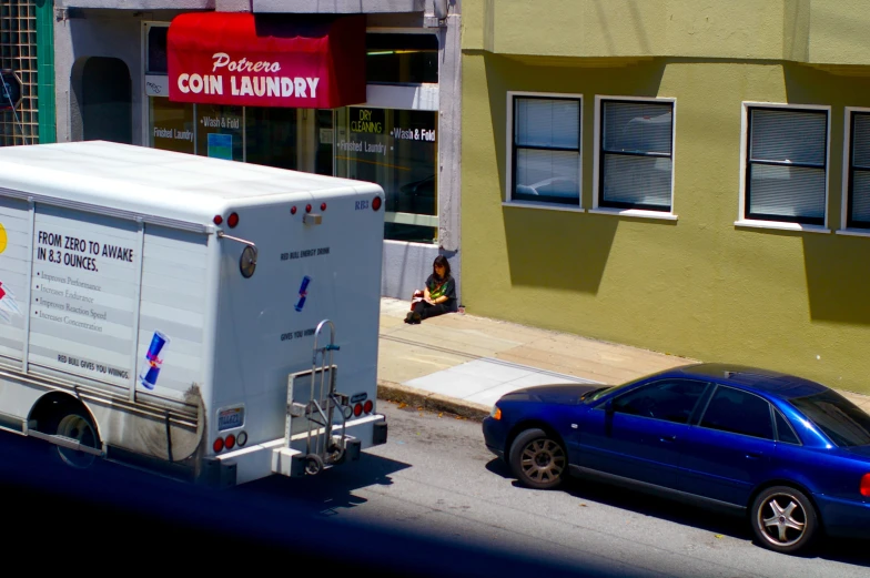 the delivery truck is parked in front of the blue car
