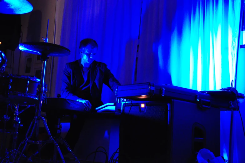 a man plays a keyboard and sound equipment in the dark