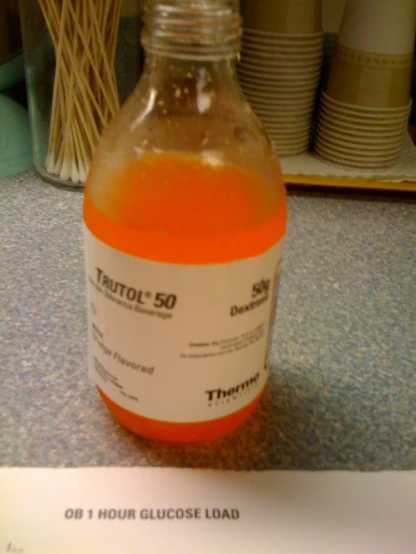 a bottle filled with orange liquid sitting on top of a counter