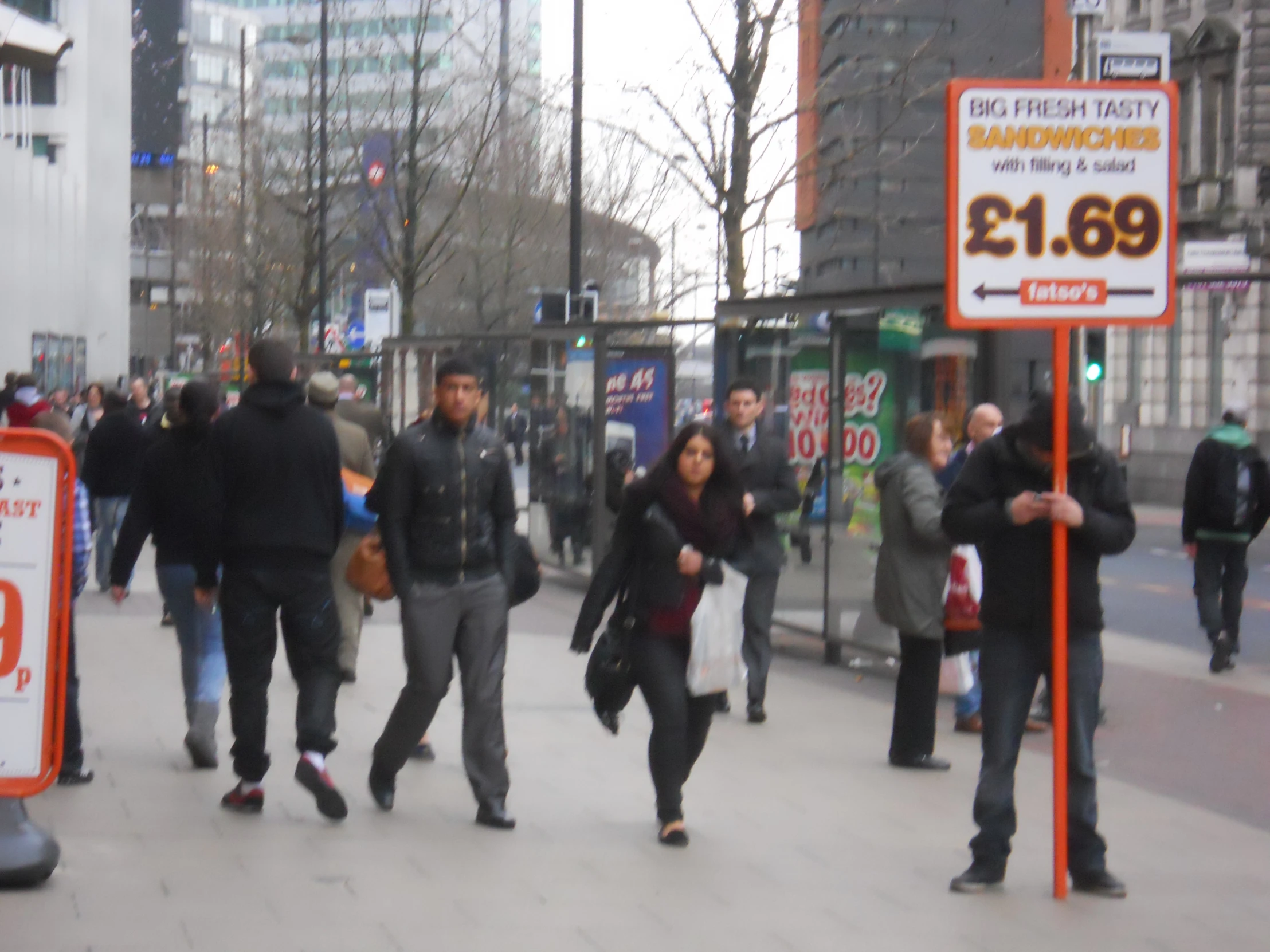 group of people walking down a street next to tall buildings