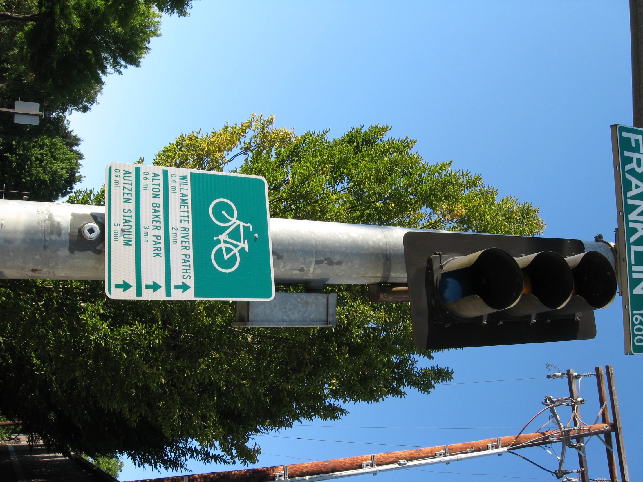 street signs are hung on a pole near traffic lights