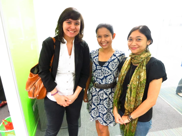 two woman smiling and standing next to each other in an office