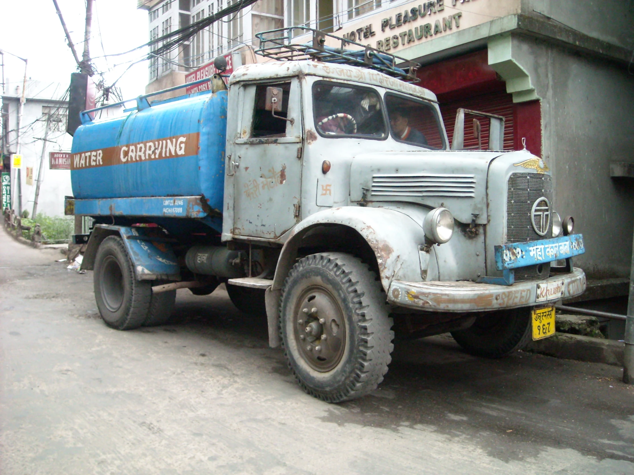 an old blue truck sitting on the side of the street