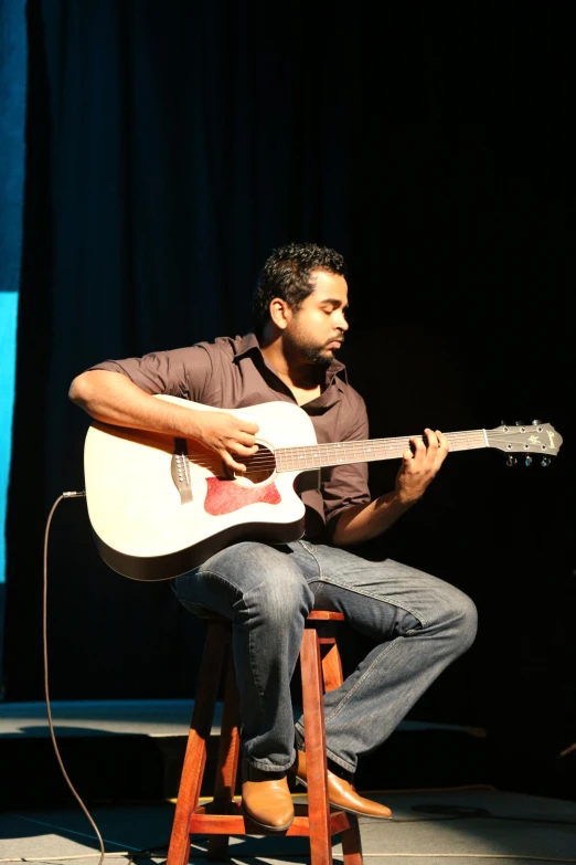 a man with a guitar sitting on top of a stool