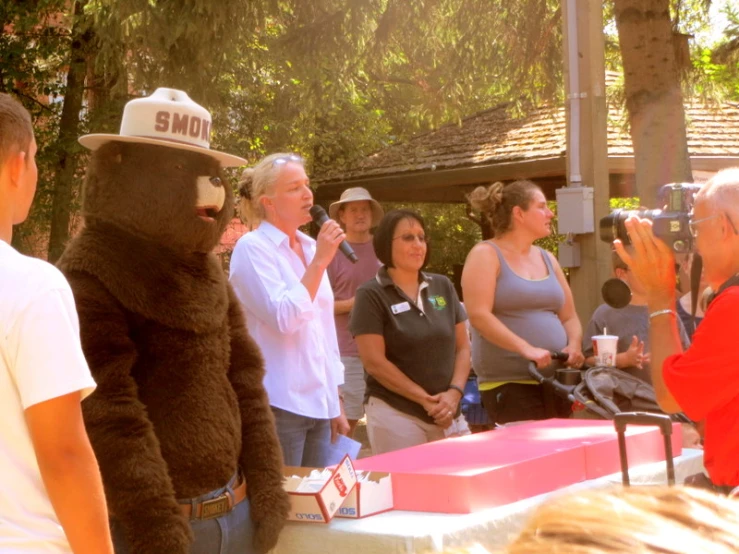 a bear man is standing by the camera while other people watch