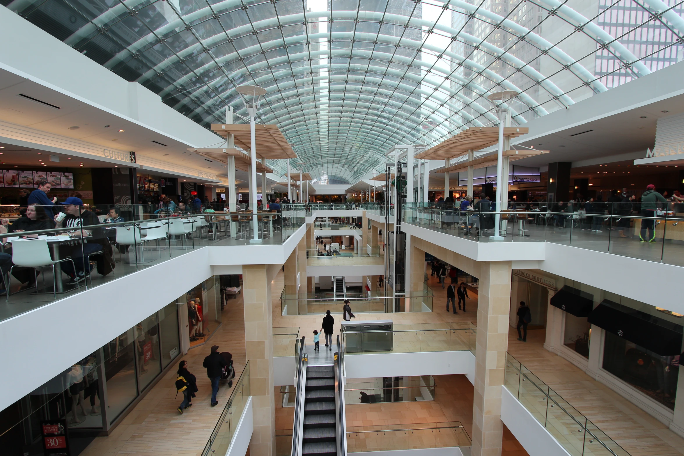 the top of an indoor mall with some people on escalators