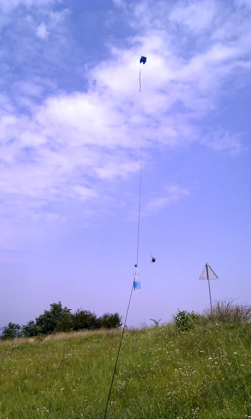 two kites flying in the air on top of a grassy field