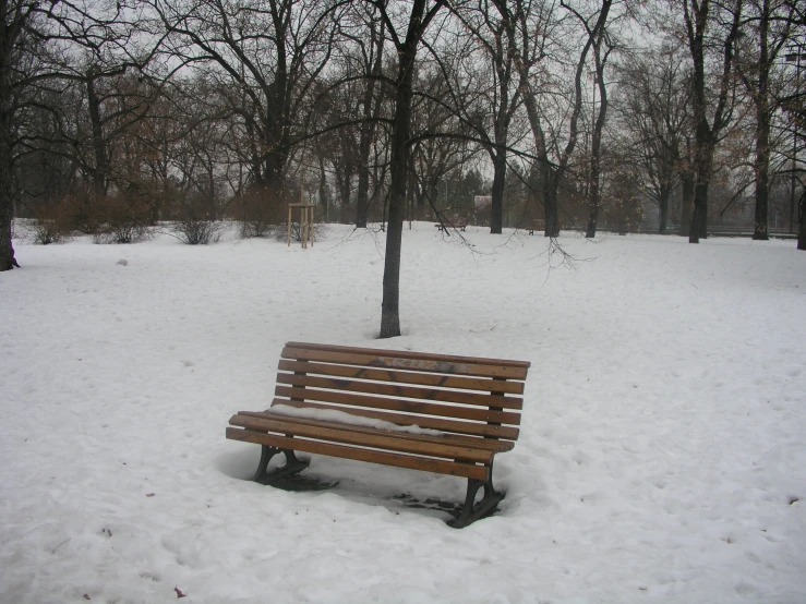a wooden bench covered in snow with no one on it