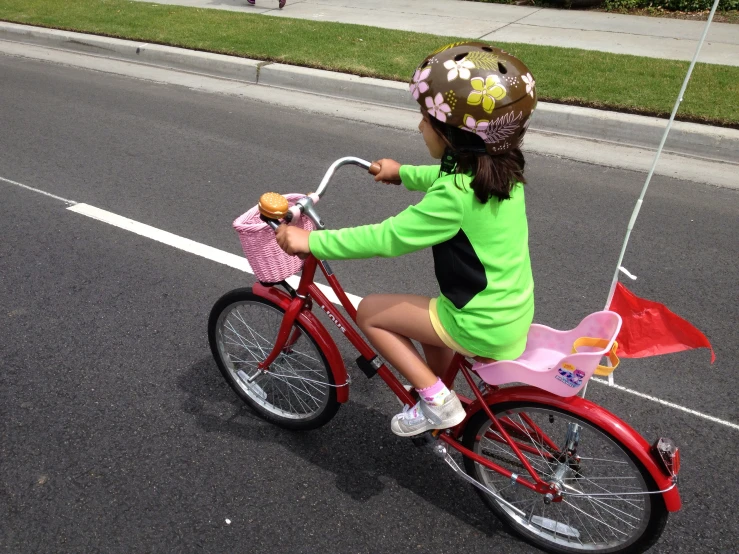 a little girl riding on a bicycle down the street