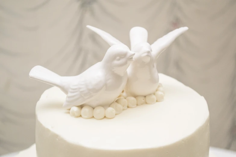 two white birds that are on top of a cake