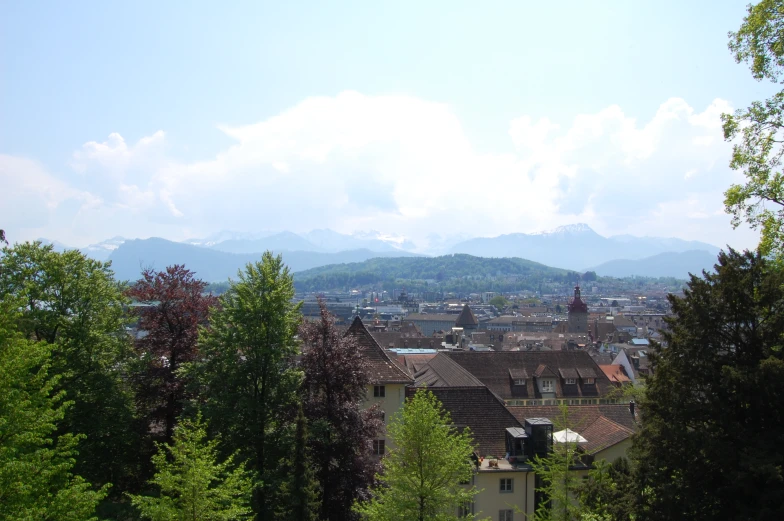 a mountain covered in clouds and trees next to the town