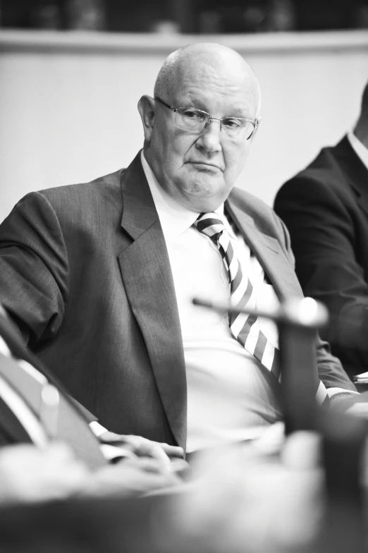 a man is sitting at a desk in a suit