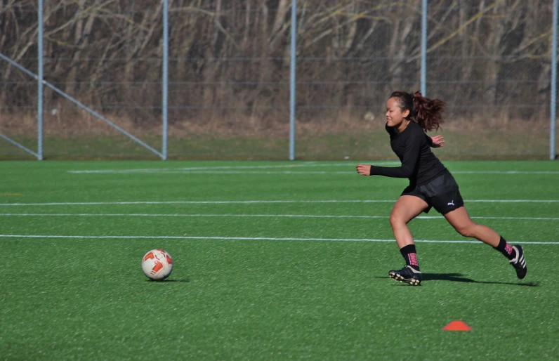 a woman is running after a soccer ball