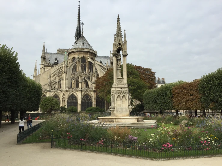 a tall building with towers and two pillars with flowers growing in front of it