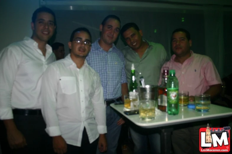 four men are standing around a table full of bottles