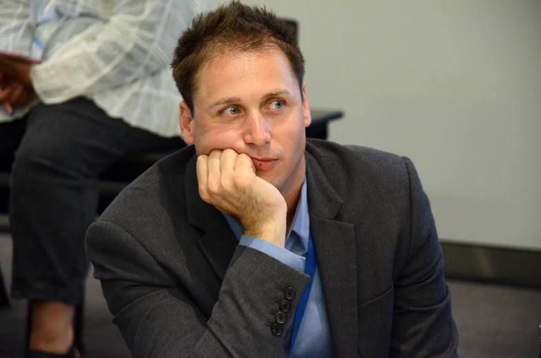 a man sitting in front of a computer desk in a suit