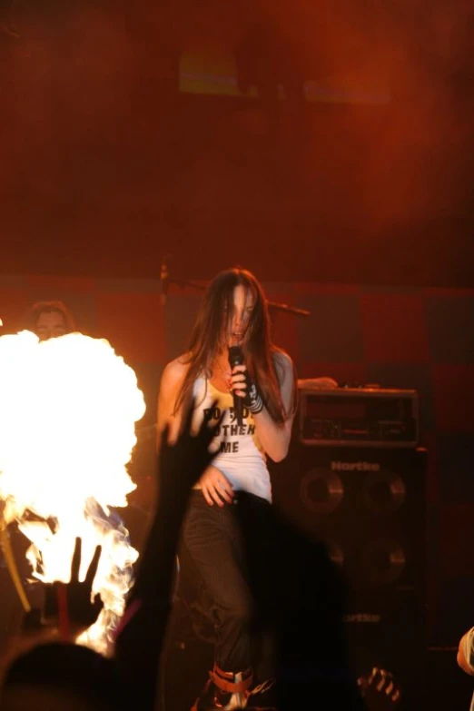 a person holding a microphone in front of a fireball
