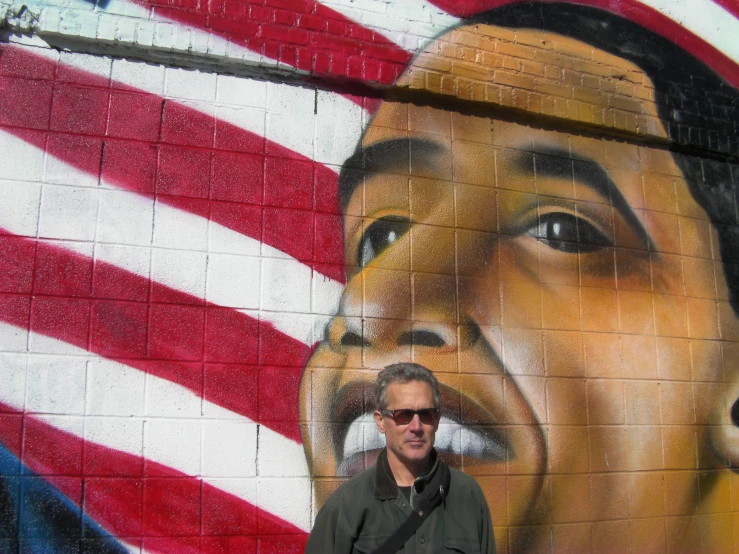 the man is posing next to the obama graffiti
