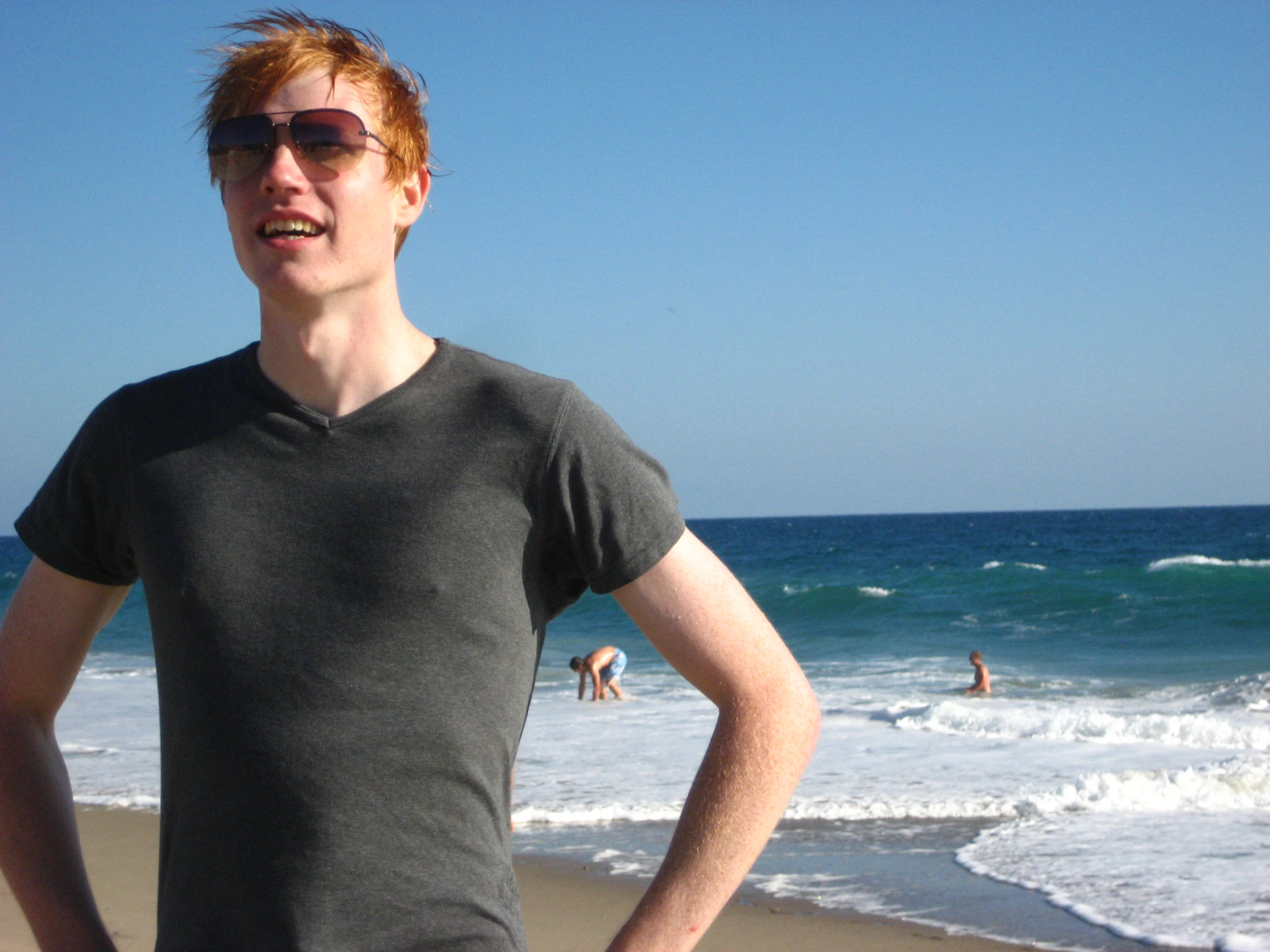 a boy is standing on the beach with his hands in his pockets