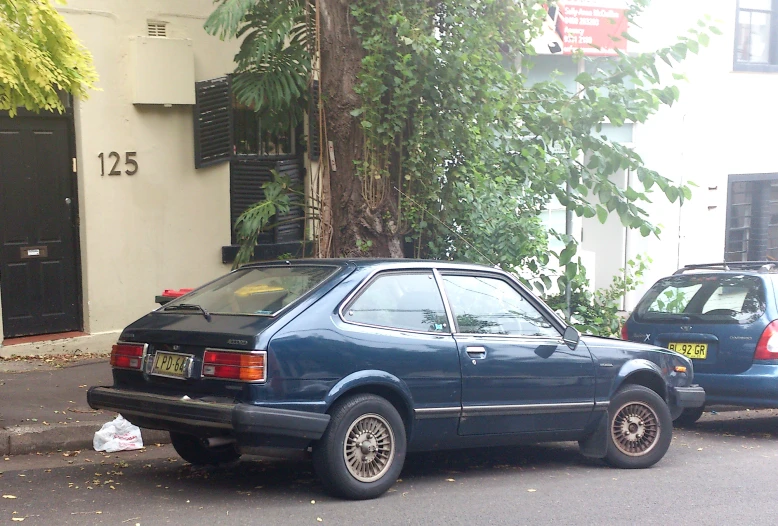 two blue cars parked on the side of a road