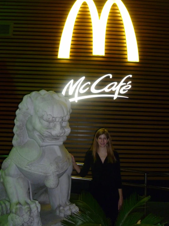 a woman standing next to a lion statue outside of a restaurant