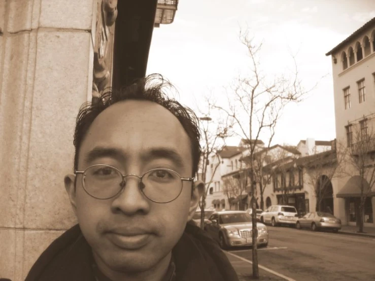 a man with glasses, standing on the sidewalk
