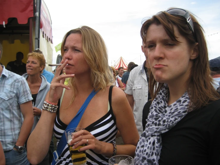 three women are talking in a crowd and drinking beverages
