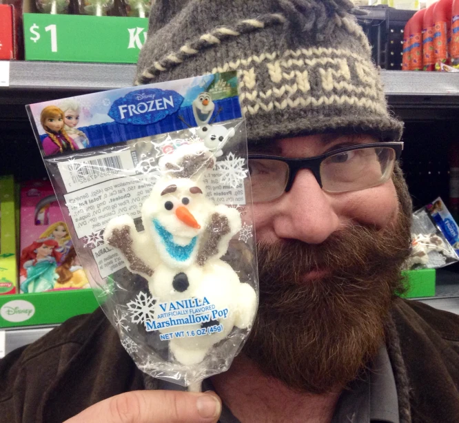 a bearded man in a hat holds up a frozen snowman ornament