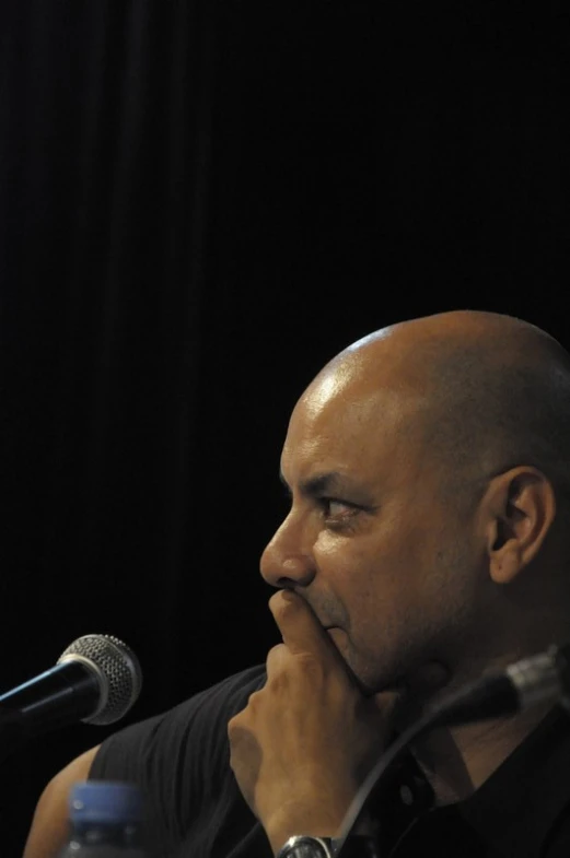 a man holding his hand over his face in front of a microphone