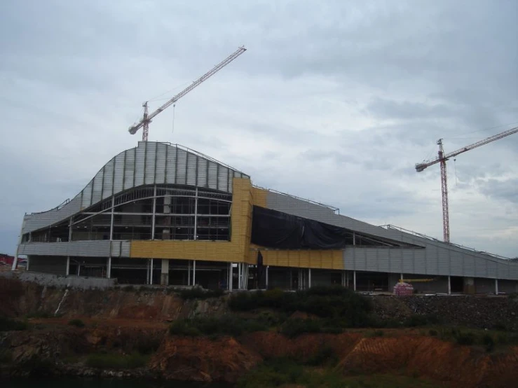 there are two cranes near a building under construction