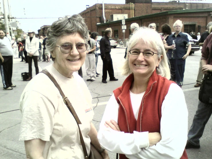 two woman smiling at the camera and some people