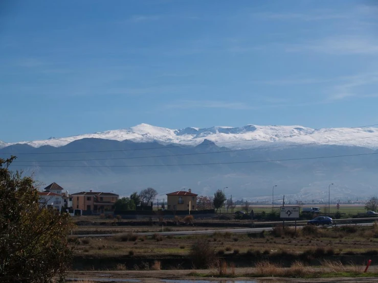 a snowy mountain rises over a valley in the distance