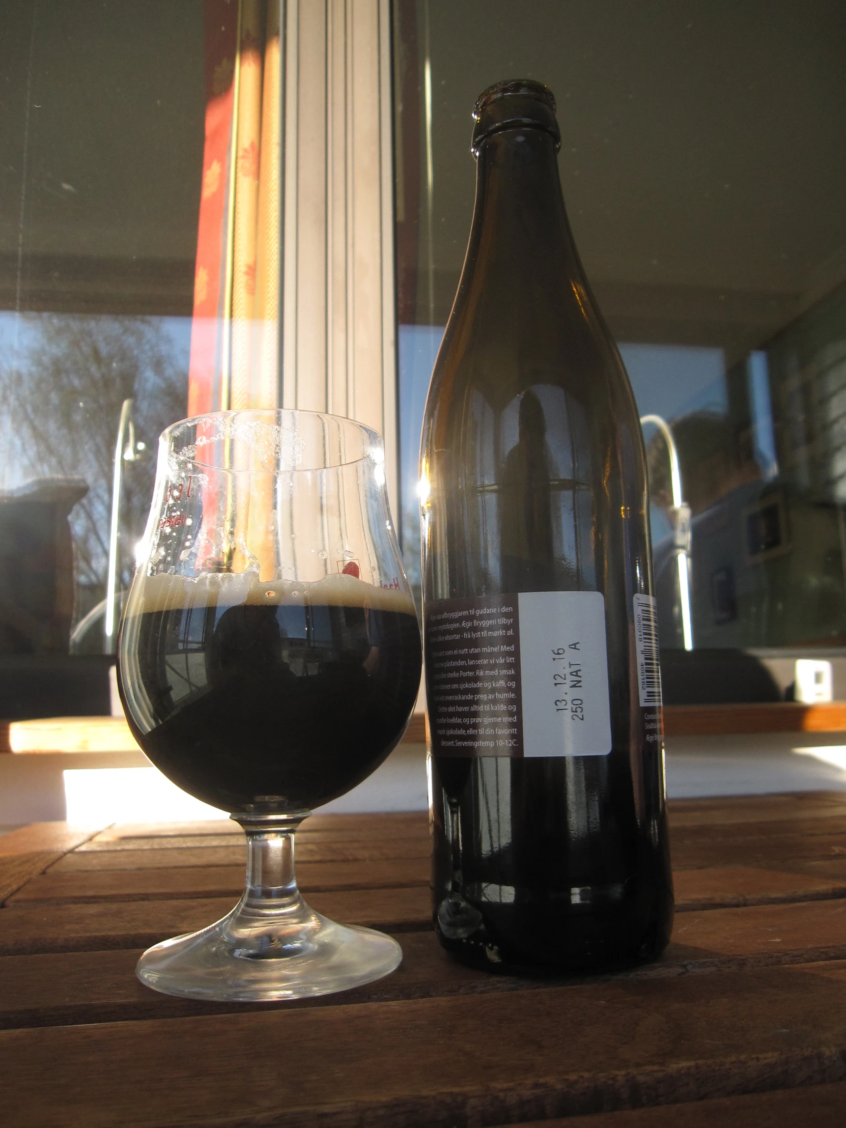 a glass and bottle sitting on top of a wooden table