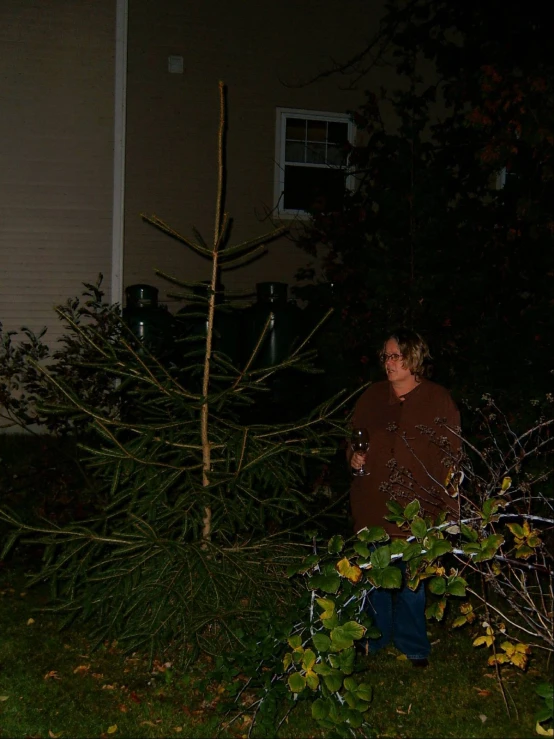 the woman is standing by the trees in her backyard