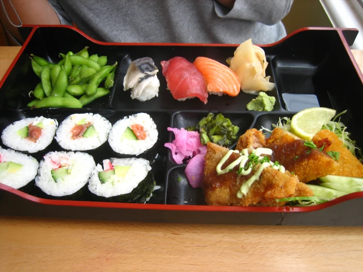 several kinds of sushi in a black tray