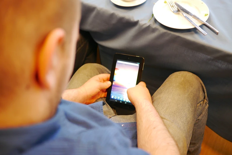 man holding and looking at cellphone in room