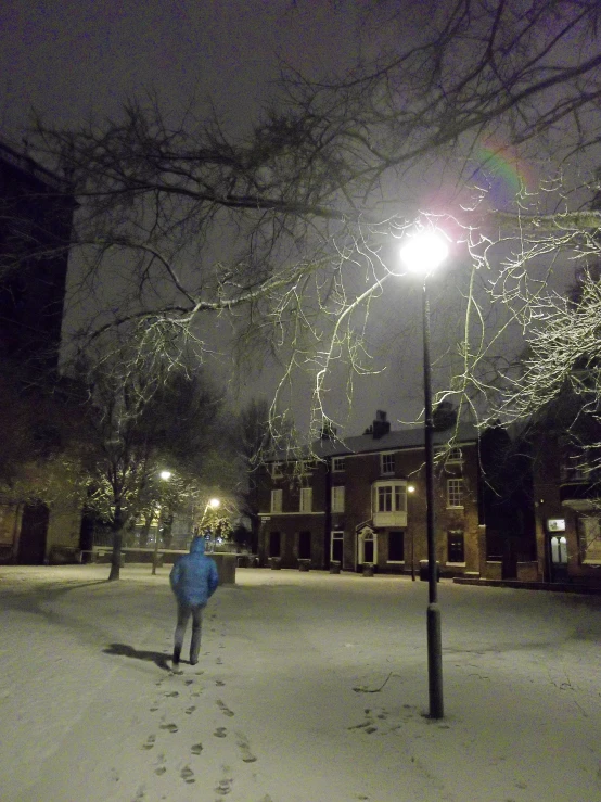 a snowy sidewalk with lights and a person walking on it