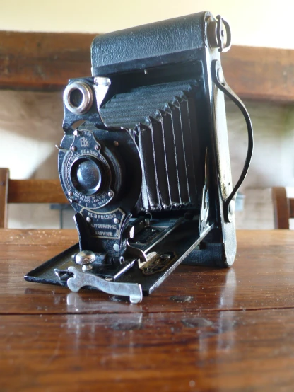 an old style camera sitting on top of a wooden table