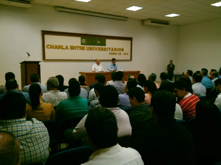 a man is standing at a podium giving a lecture to a crowd