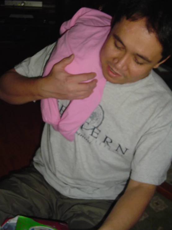 a man sitting on the floor while holding onto his pink shirt