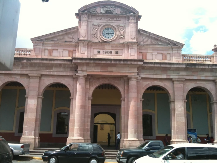 cars parked outside of a large, ornate pink building