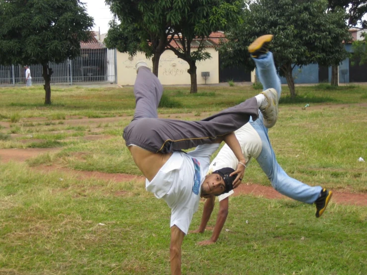 two men perform tricks in a grassy area