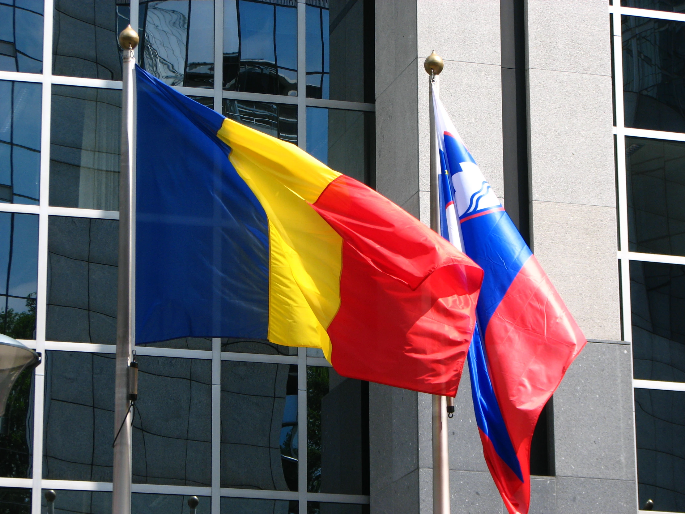 two flags are standing outside in front of a building