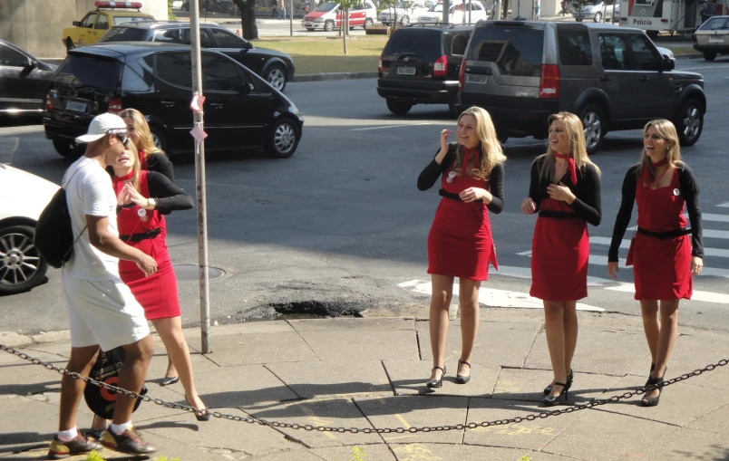 four beautiful women in red dresses standing on the sidewalk