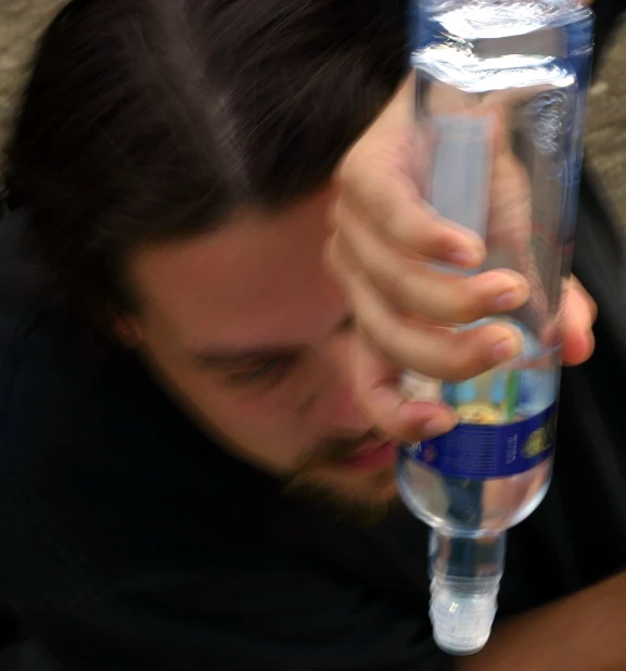 a man holds a water bottle and touches it to his face