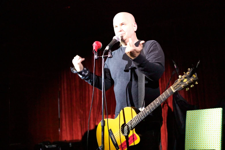 the man is singing in front of the microphone and playing a guitar